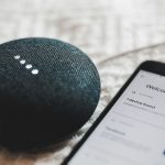 Turned-on charcoal Google Home Mini and smartphone photo - systech